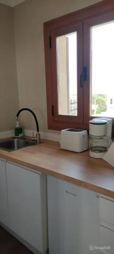 a kitchen counter with a sink and a window at Apartamentos Can Salas in Cala Figuera
