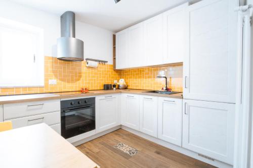 a white kitchen with white cabinets and a wooden floor at La Pinta in Mola di Bari