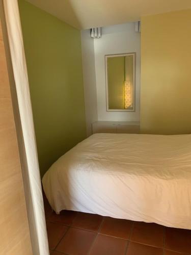 une petite chambre avec un lit et un miroir dans l'établissement Vert Luisant, aux Issambres
