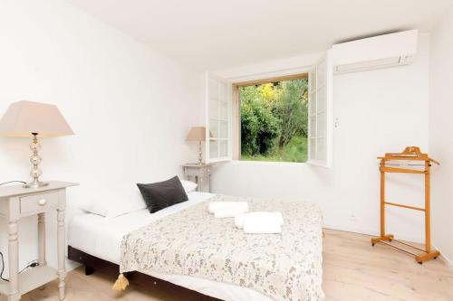 a white bedroom with a bed and a window at Bastide Provençale,Piscine in Cabris