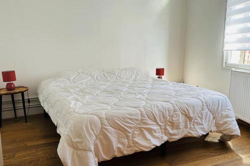 a bed in a bedroom with a white comforter at La Hourdeloise appartement 100m de la mer à Cayeux in Cayeux-sur-Mer