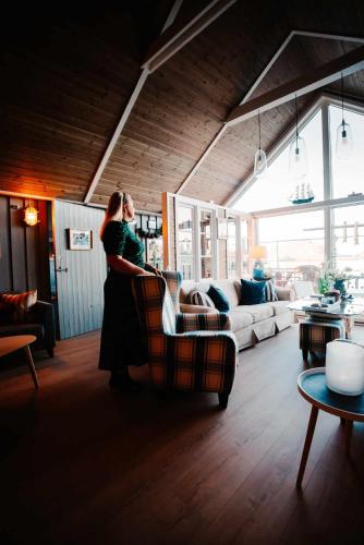 a woman standing in a living room with a couch at Kræmmervika Havn in Ballstad