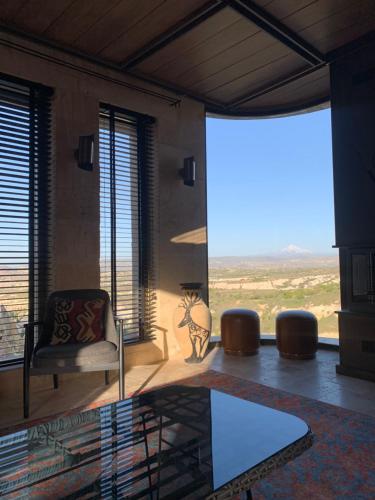 a living room with a chair and a large window at Very Peri Cappadocia - The Lifestyle Luxury Design Hotel in Uchisar