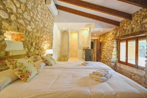 - un grand lit dans une chambre dotée d'un mur en pierre dans l'établissement Sestadors, à La Puebla