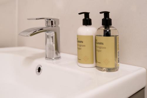 two bottles of soap sitting on a bathroom sink at No.3 Mill Park a luxury self-catering apartment in Donegal