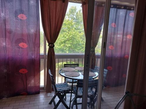 un balcon avec une table, des chaises et une fenêtre dans l'établissement T2 residence alhambra avec piscine a 800 m plage richelieu et 300m ile des loisirs, au Cap d'Agde