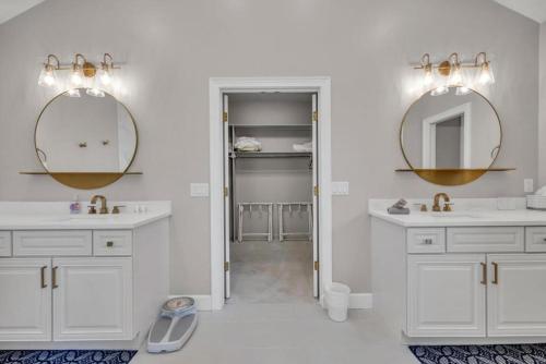 a white bathroom with two sinks and two mirrors at Club Views - Pool Home in Ponte Vedra Beach