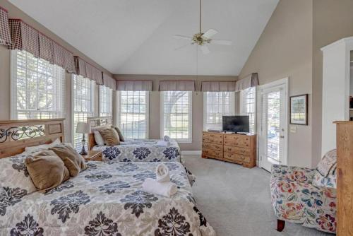 a bedroom with two beds and a tv and windows at Club Views - Pool Home in Ponte Vedra Beach