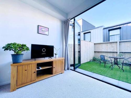 a living room with a television on a wooden cabinet at New townhouse with garden in the city centre in Auckland