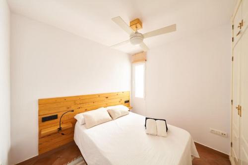 Un dormitorio con una cama blanca con ventilador de techo. en Bogavante, en La Isleta del Moro