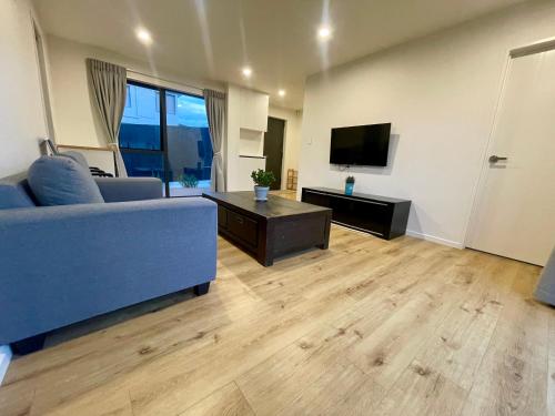 a living room with a blue couch and a television at Free carpark, 4-bedroom house in Auckland