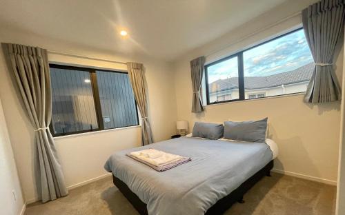 a bedroom with a bed and two large windows at Free carpark, 4-bedroom house in Auckland