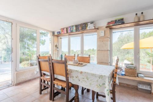 a dining room with a table and chairs and windows at Casa Vista Monte in Llucmajor