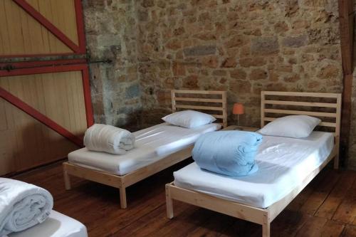 2 camas individuales en una habitación con una pared de ladrillo en Grande maison, avec piscine privée et belle vue, en Ambeyrac