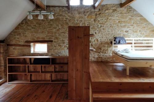 Un dormitorio con una cama y una pared de piedra. en Grande maison, avec piscine privée et belle vue, en Ambeyrac
