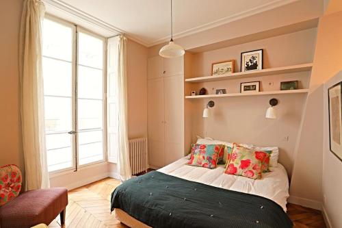 une chambre avec un lit et une grande fenêtre dans l'établissement Beautiful apartment Jardin Luxemboug rue Férou, à Paris