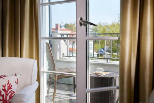 a room with a door open to a balcony with a chair at Strandhotel Zingst in Zingst