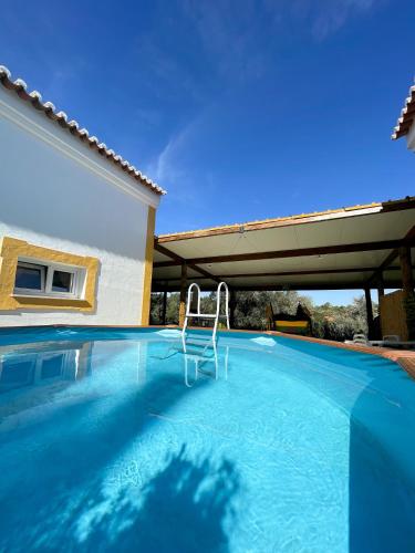 a swimming pool with a chair in front of a house at MONTE DAS AREIAS CASA DE CAMPO/PASSADIÇO/PATEO/RAMPA in Porches