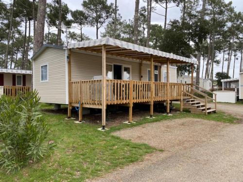 un mobil-home avec un porche et une terrasse dans l'établissement Les Dunes de Contis 4 étoiles emplacement T001 3CH 1SDB 6-8 personnes, à Saint-Julien-en-Born