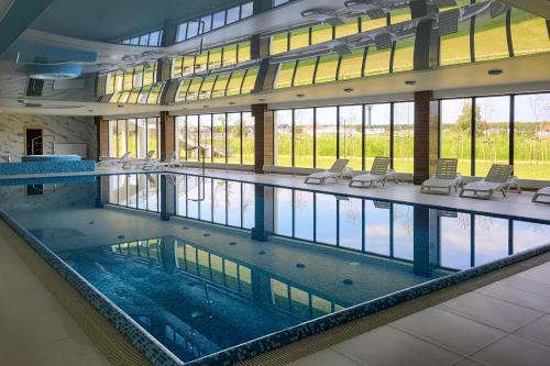 a large swimming pool in a building with chairs at Eleganckie Studio Basen, Fitness & Balkon by Noclegi Renters in Dziwnów