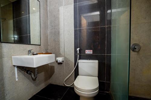 a bathroom with a white toilet and a sink at Hotel Blambangan in Banyuwangi