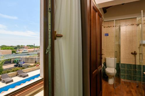 a bathroom with a toilet and a balcony with a view at VILLA GINA in Valtura