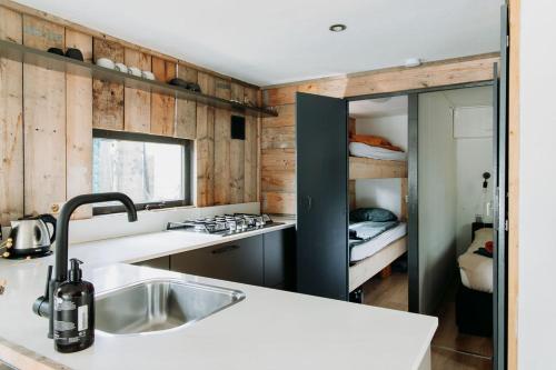 a kitchen with a sink and a kitchen with a bedroom at Tiny Cabin Mae op de Veluwe in Putten
