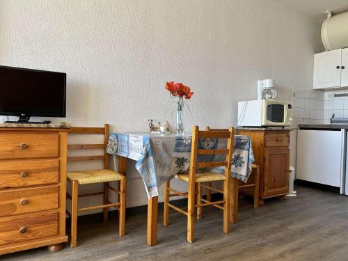 une cuisine avec une table, deux chaises et un four micro-ondes dans l'établissement Studio bord de mer, parking, animaux admis - FR-1-229D-226, à Saint Pierre La Mer