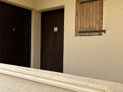 une paire de portes sur un bâtiment avec fenêtre dans l'établissement Studio bord de mer, parking, animaux admis - FR-1-229D-226, à Saint Pierre La Mer