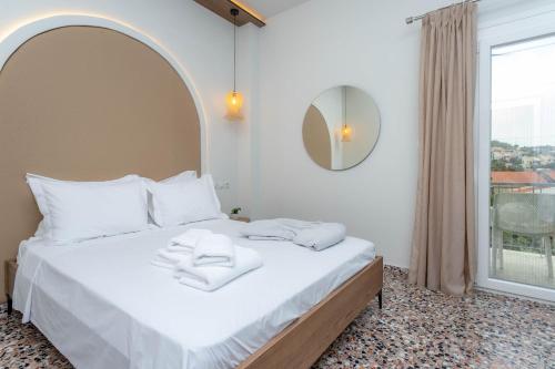 a bedroom with a bed with a mirror and a window at Pteleo Apartments in Pteleós