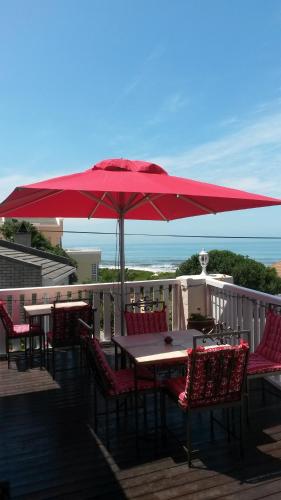 a table and chairs under an umbrella on a deck at Belle Vue Guesthouse in Hermanus