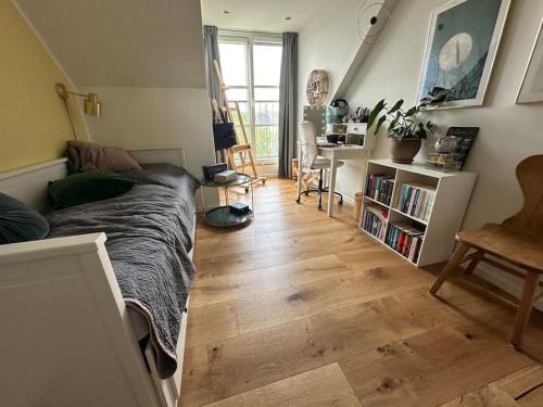 a living room with a bed and a wooden floor at Penthouse med egen tagterrasse in Copenhagen