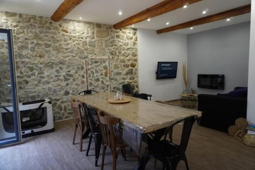 - un salon avec un mur en pierre, une table et des chaises dans l'établissement Jacobins-6 pers-Proche mer-Calme, à Lapalme