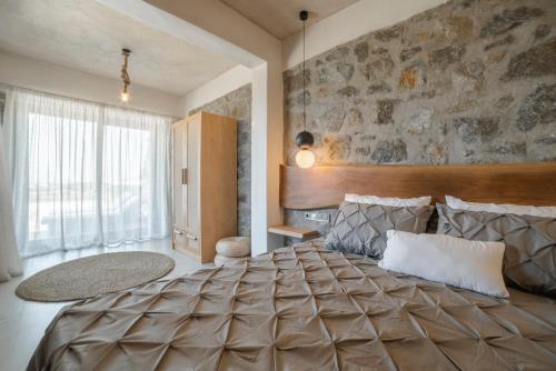 een slaapkamer met een groot bed en een stenen muur bij Naxos Privilege Villas in Agia Anna Naxos