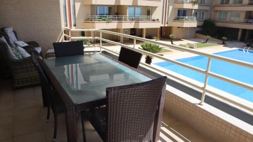 a table and chairs on a balcony with a swimming pool at Pool and sea view accommodation 50 m sea in Furadouro