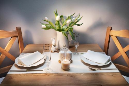 a wooden table with a vase of white flowers and napkins at Penzion Pawlowitz in Velké Pavlovice
