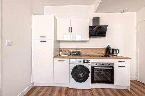 une cuisine avec des armoires blanches et une machine à laver dans l'établissement Appartement Heol-Moderne Quatre-moulins, à Brest