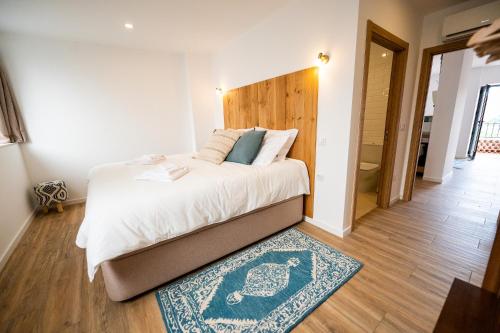a bedroom with a bed with a wooden headboard and a rug at Mira D'Ouro Sertã in Sertã