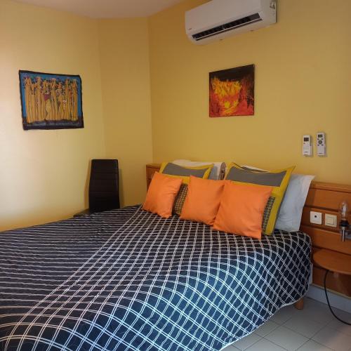 a bedroom with a bed with orange and blue pillows at MARCO POLO in Saint-François