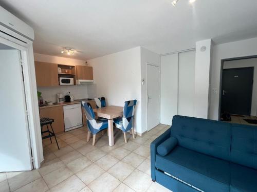 un salon avec un canapé bleu et une table dans l'établissement Appartement tout confort 4 personnes Moriani Santa Maria-Poggio, à Santa-Maria-Poggio