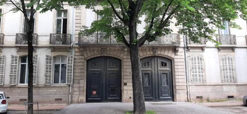 un bâtiment avec deux portes noires et un arbre dans l'établissement Appartement - Dijon centre, à Dijon