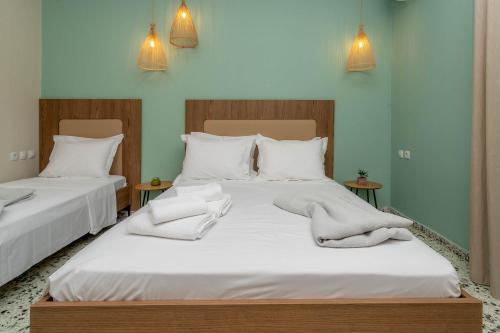 two beds in a room with white sheets and pillows at Pteleo Apartments in Pteleós