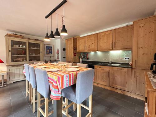 une cuisine avec une table, des chaises et des armoires dans l'établissement Duplex spacieux proche des remontées, balcon, animaux admis, WIFI - FR-1-624-13, à Samoëns