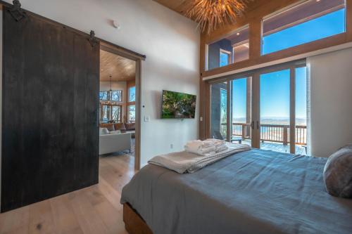 Un dormitorio con una cama grande y grandes ventanales. en Capstone - Modern Luxury Cabin Full Mountain View, en Blue Ridge