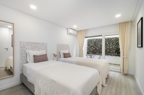 two beds in a white room with a window at Modern Villa with pool and garage by Soulplaces in Sobreda