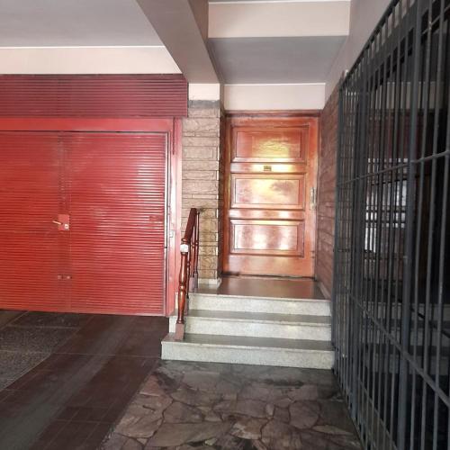 a hallway with a red door and a staircase at Hermoso departamento en Ciudad de Mendoza in Barraquero