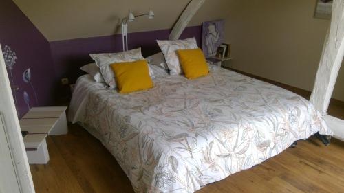 - un grand lit avec 2 oreillers jaunes dans l'établissement Chambres à la campagne, à Requeil
