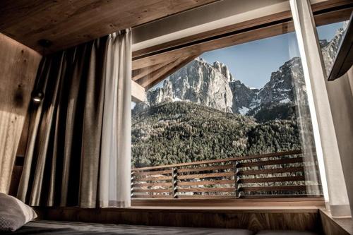 a bedroom with a window with a mountain view at Mysciliar Apartment Sky I in Siusi