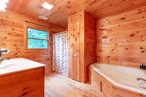 a log cabin bathroom with a tub and a sink at Hawks Hideaway in Mineral Bluff