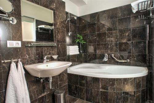 a bathroom with a sink and a tub and a mirror at Residence Rybna in Prague